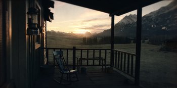 Movie still from “Togo” (2019), directed by Ericson Core – A rocking chair sitting on top of a wooden deck next to mountains; Extreme Wide shot, High angle