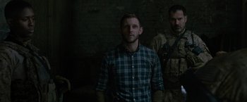 Movie still from “Without Remorse” (2021), directed by Stefano Sollima – A man standing next to another man in a dark room; Medium shot, Over the shoulder angle