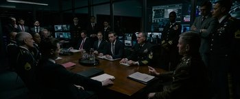 Movie still from “Without Remorse” (2021), directed by Stefano Sollima – A group of men sitting at a table in a room; Wide shot, Over the shoulder angle