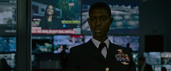 Movie still from “Without Remorse” (2021), directed by Stefano Sollima – A man in a military uniform standing in front of a wall of television screens; Close Up shot, Over the shoulder angle