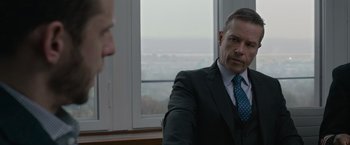 Movie still from “Without Remorse” (2021), directed by Stefano Sollima – A man wearing a suit and tie in front of a window; Close Up shot, Over the shoulder angle