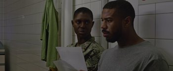 Movie still from “Without Remorse” (2021), directed by Stefano Sollima – Two men standing next to each other holding papers; Medium shot, Over the shoulder angle