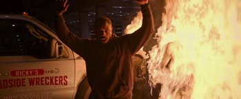 Movie still from “Without Remorse” (2021), directed by Stefano Sollima – A man standing in front of a car fire; Medium shot, Low angle