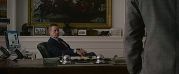 Movie still from “Without Remorse” (2021), directed by Stefano Sollima – A man sitting at a desk in front of a painting; Medium shot, Over the shoulder angle