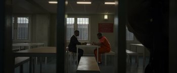 Movie still from “Without Remorse” (2021), directed by Stefano Sollima – Two men sitting at a table in a jail cell; Wide shot, Over the shoulder angle