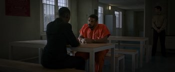 Movie still from “Without Remorse” (2021), directed by Stefano Sollima – Two men sitting at a table in a jail cell; Wide shot, Over the shoulder angle