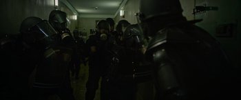 Movie still from “Without Remorse” (2021), directed by Stefano Sollima – A group of men in black suits and gas masks in a hallway; Medium shot, Low angle