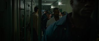 Movie still from “Without Remorse” (2021), directed by Stefano Sollima – A group of people in a hallway with a police officer on one side of the hallway; Medium shot, Over the shoulder angle