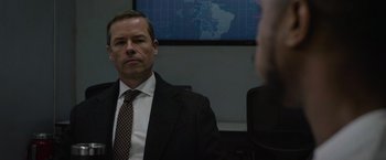 Movie still from “Without Remorse” (2021), directed by Stefano Sollima – A man wearing a suit and tie in front of a monitor; Close Up shot, Over the shoulder angle