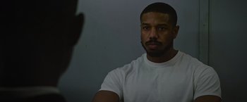 Movie still from “Without Remorse” (2021), directed by Stefano Sollima – A man in a white t - shirt is taking a picture; Close Up shot, Over the shoulder angle