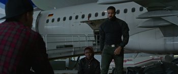 Movie still from “Without Remorse” (2021), directed by Stefano Sollima – A man standing next to another man near a plane; Medium shot, Over the shoulder angle