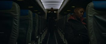 Movie still from “Without Remorse” (2021), directed by Stefano Sollima – A man standing on an aisle of an airplane at night; Medium shot, Low angle