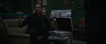 Movie still from “Without Remorse” (2021), directed by Stefano Sollima – A man sitting in front of an open briefcase; Medium shot, Over the shoulder angle