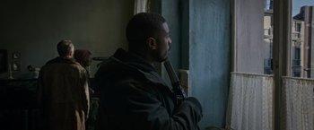 Movie still from “Without Remorse” (2021), directed by Stefano Sollima – A man holding a knife up to his face; Medium shot, Over the shoulder angle