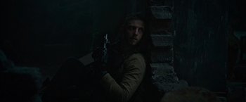 Movie still from “Without Remorse” (2021), directed by Stefano Sollima – A man holding a gun while sitting in a dark room; Medium shot, Over the shoulder angle