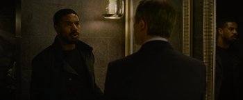 Movie still from “Without Remorse” (2021), directed by Stefano Sollima – Two men in suits are talking in a bathroom; Medium shot, Over the shoulder angle
