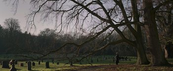 Movie still from “Without Remorse” (2021), directed by Stefano Sollima – A person walking in a field near a large tree; Extreme Wide shot, High angle
