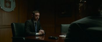 Movie still from “Without Remorse” (2021), directed by Stefano Sollima – A man sitting at a table in front of a phone; Medium shot, Over the shoulder angle