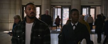 Movie still from “Without Remorse” (2021), directed by Stefano Sollima – Two men are standing in a hallway in front of a building; Medium shot, Over the shoulder angle