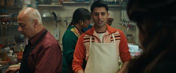 Movie still from “Tomb Raider” (2018), directed by Roar Uthaug – A man wearing an apron standing in a kitchen; Medium shot, Over the shoulder angle