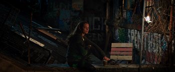 Movie still from “Tomb Raider” (2018), directed by Roar Uthaug – A woman sitting on the ground with a cup of coffee; Wide shot, High angle