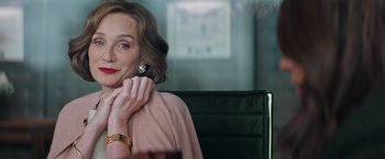 Movie still from “Tomb Raider” (2018), directed by Roar Uthaug – A woman sitting in a chair holding a cell phone to her ear; Close Up shot, Over the shoulder angle