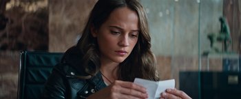 Movie still from “Tomb Raider” (2018), directed by Roar Uthaug – A woman looking down at a piece of paper; Close Up shot, Over the shoulder angle