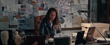 Movie still from “Tomb Raider” (2018), directed by Roar Uthaug – A woman sitting at a desk in front of a computer; Medium shot, High angle