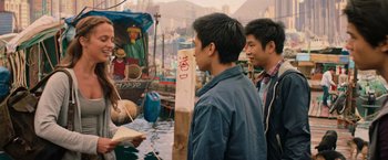 Movie still from “Tomb Raider” (2018), directed by Roar Uthaug – Two young men standing next to each other in front of a boat; Medium shot, Over the shoulder angle