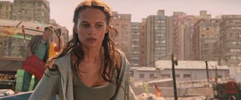 Movie still from “Tomb Raider” (2018), directed by Roar Uthaug – A woman standing on top of a building near a city; Close Up shot, Over the shoulder angle