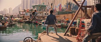 Movie still from “Tomb Raider” (2018), directed by Roar Uthaug – A man standing on a dock near a body of water; Wide shot, High angle