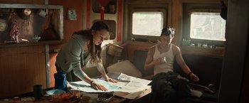 Movie still from “Tomb Raider” (2018), directed by Roar Uthaug – A woman and a man looking at a map in front of a window; Medium shot, High angle