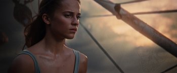 Movie still from “Tomb Raider” (2018), directed by Roar Uthaug – A beautiful young woman holding an open umbrella; Close Up shot, Low angle