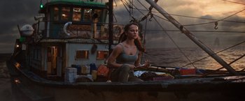 Movie still from “Tomb Raider” (2018), directed by Roar Uthaug – A woman sitting on the deck of a boat in the ocean; Medium shot, Low angle