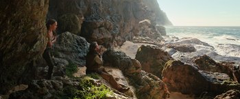 Movie still from “Tomb Raider” (2018), directed by Roar Uthaug – A man sitting on the rocks near the water; Wide shot, Low angle