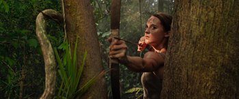 Movie still from “Tomb Raider” (2018), directed by Roar Uthaug – A woman holding a bow and arrow in the woods; Close Up shot, Low angle