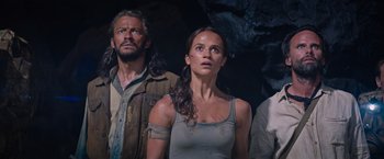 Movie still from “Tomb Raider” (2018), directed by Roar Uthaug – A man and a woman standing next to each other in a cave; Medium shot, Low angle