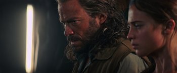 Movie still from “Tomb Raider” (2018), directed by Roar Uthaug – A person with long hair and a beard; Close Up shot, Over the shoulder angle