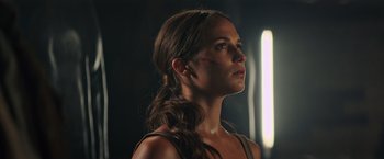 Movie still from “Tomb Raider” (2018), directed by Roar Uthaug – A beautiful young woman with long brown hair; Close Up shot, Low angle