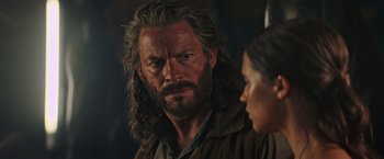 Movie still from “Tomb Raider” (2018), directed by Roar Uthaug – A person with long hair and a beard; Close Up shot, Over the shoulder angle