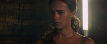 Movie still from “Tomb Raider” (2018), directed by Roar Uthaug – A person with long brown hair; Close Up shot, Over the shoulder angle