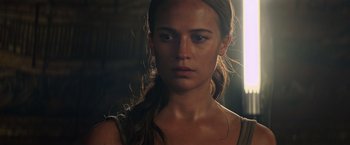 Movie still from “Tomb Raider” (2018), directed by Roar Uthaug – A person with long brown hair; Close Up shot, Over the shoulder angle