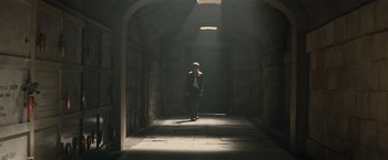 Movie still from “Tomb Raider” (2018), directed by Roar Uthaug – A man standing in a dark hallway with light coming from the ceiling; Wide shot, Low angle