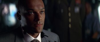 Movie still from “Tomorrow Never Dies” (1997), directed by Roger Spottiswoode – A person wearing a suit and tie; Close Up shot, Over the shoulder angle