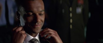 Movie still from “Tomorrow Never Dies” (1997), directed by Roger Spottiswoode – A person wearing a suit and tie; Close Up shot, Over the shoulder angle