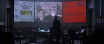 Movie still from “Tomorrow Never Dies” (1997), directed by Roger Spottiswoode – A man standing in front of a projection screen; Medium shot, Over the shoulder angle