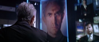 Movie still from “Tomorrow Never Dies” (1997), directed by Roger Spottiswoode – An older man looking at a picture of himself; Close Up shot, Over the shoulder angle