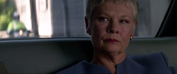 Movie still from “Tomorrow Never Dies” (1997), directed by Roger Spottiswoode – An older woman sitting in front of a window; Close Up shot, Low angle