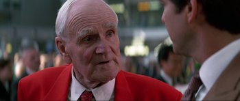 Movie still from “Tomorrow Never Dies” (1997), directed by Roger Spottiswoode – An older man wearing a red jacket talking to a younger man; Close Up shot, Over the shoulder angle