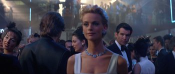 Movie still from “Tomorrow Never Dies” (1997), directed by Roger Spottiswoode – A woman in a white dress at an event; Medium shot, Over the shoulder angle